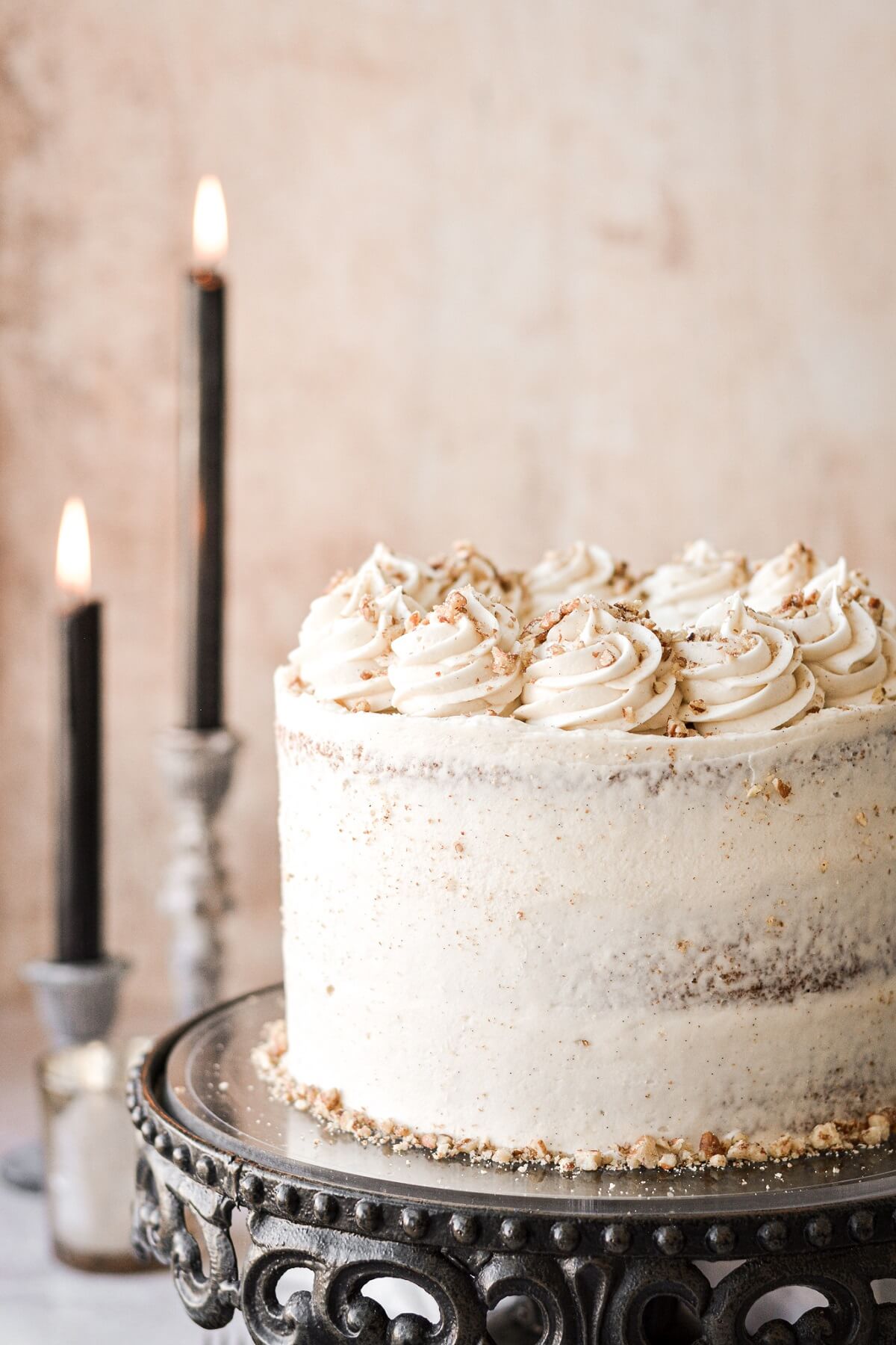 Swirls of buttercream and chopped pecans on top of a carrot cake.