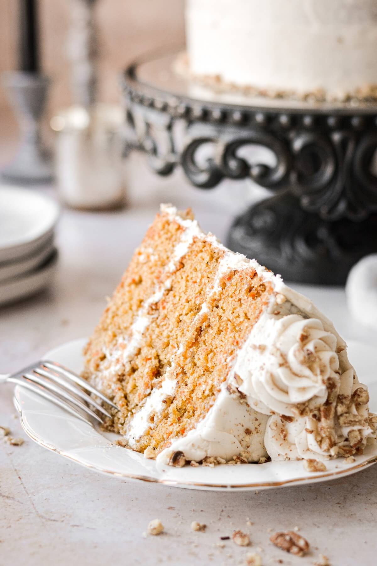 A slice of carrot cake with chopped pecans.