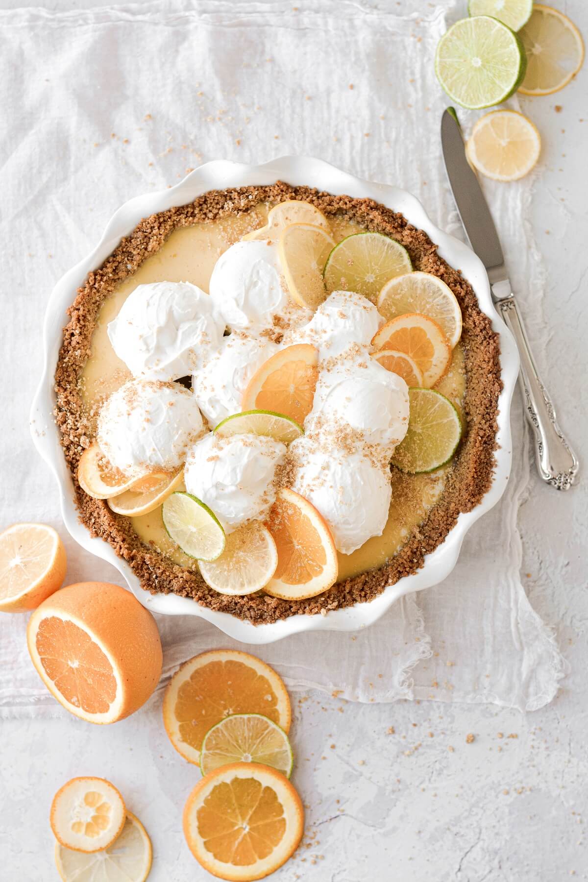 Citrus sour cream pie topped with whipped cream and citrus slices.