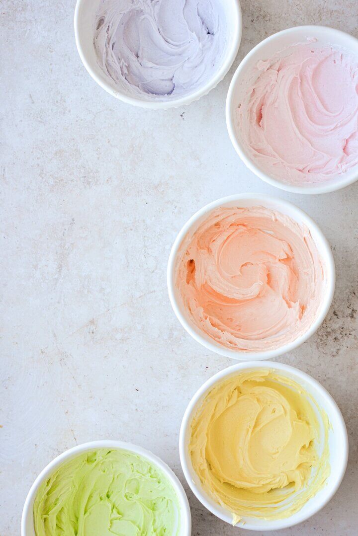 Bowls of purple, pink, orange, yellow and green pastel buttercream.