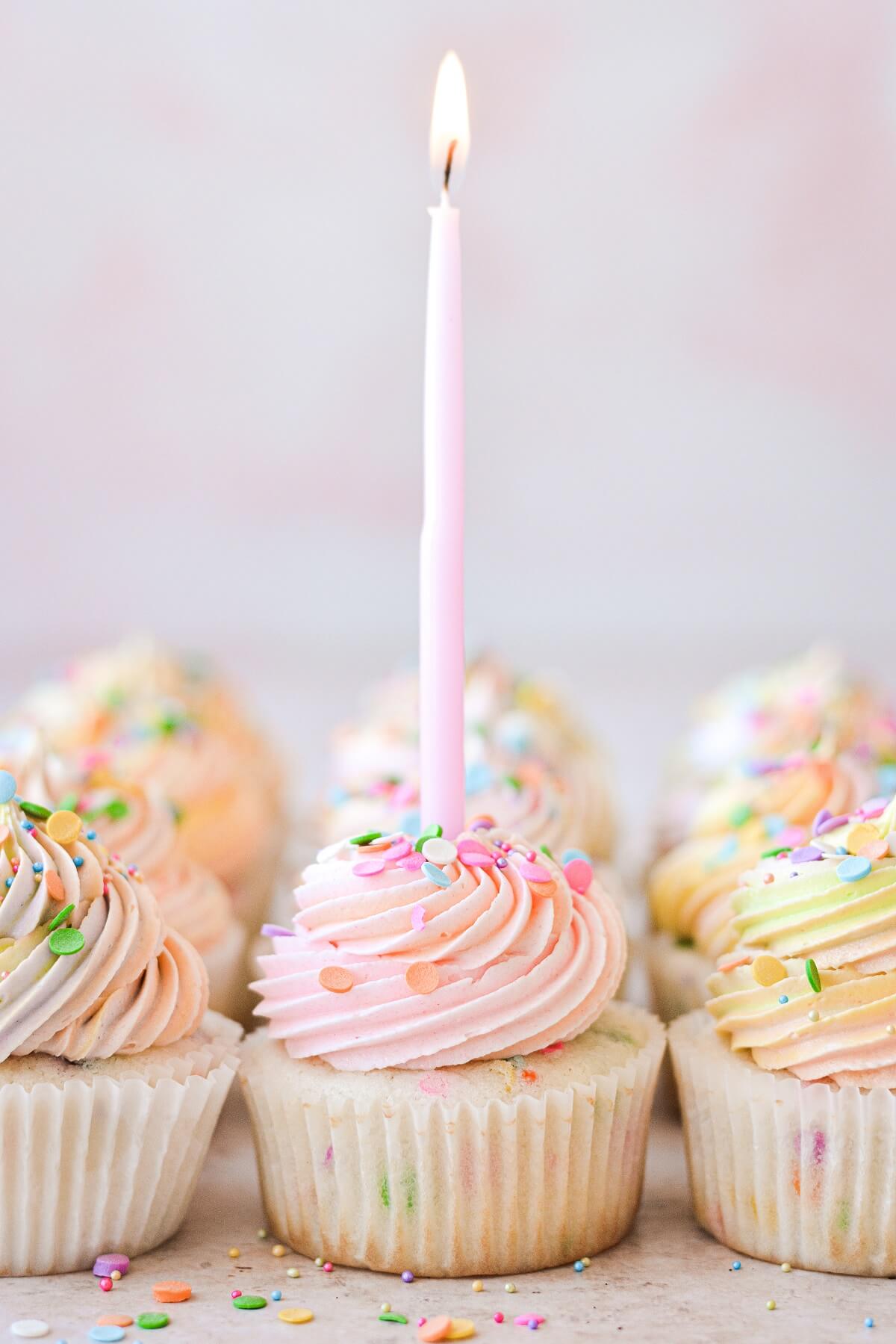 Funfetti cupcakes with sprinkles and a pink candle.