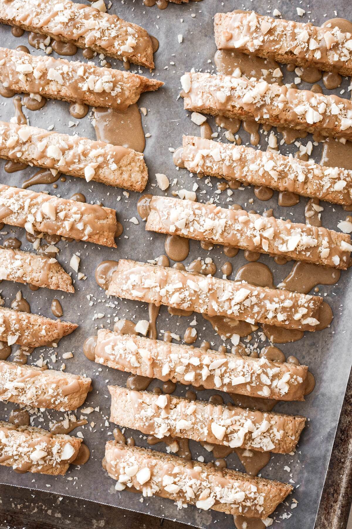 Maple biscotti drizzled with icing and sprinkled with chopped macadamia nuts.