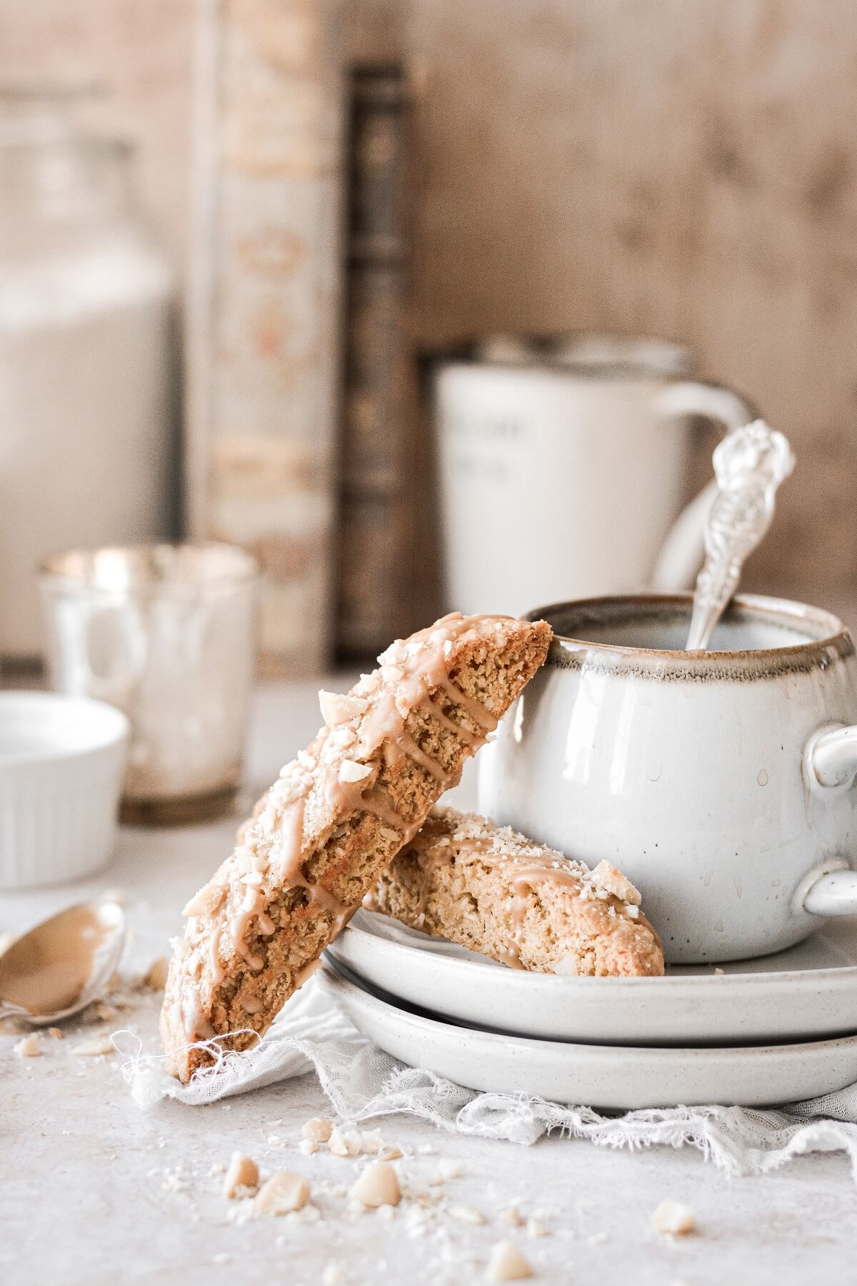 Maple biscotti with macadamia nuts resting against a cup of coffee.