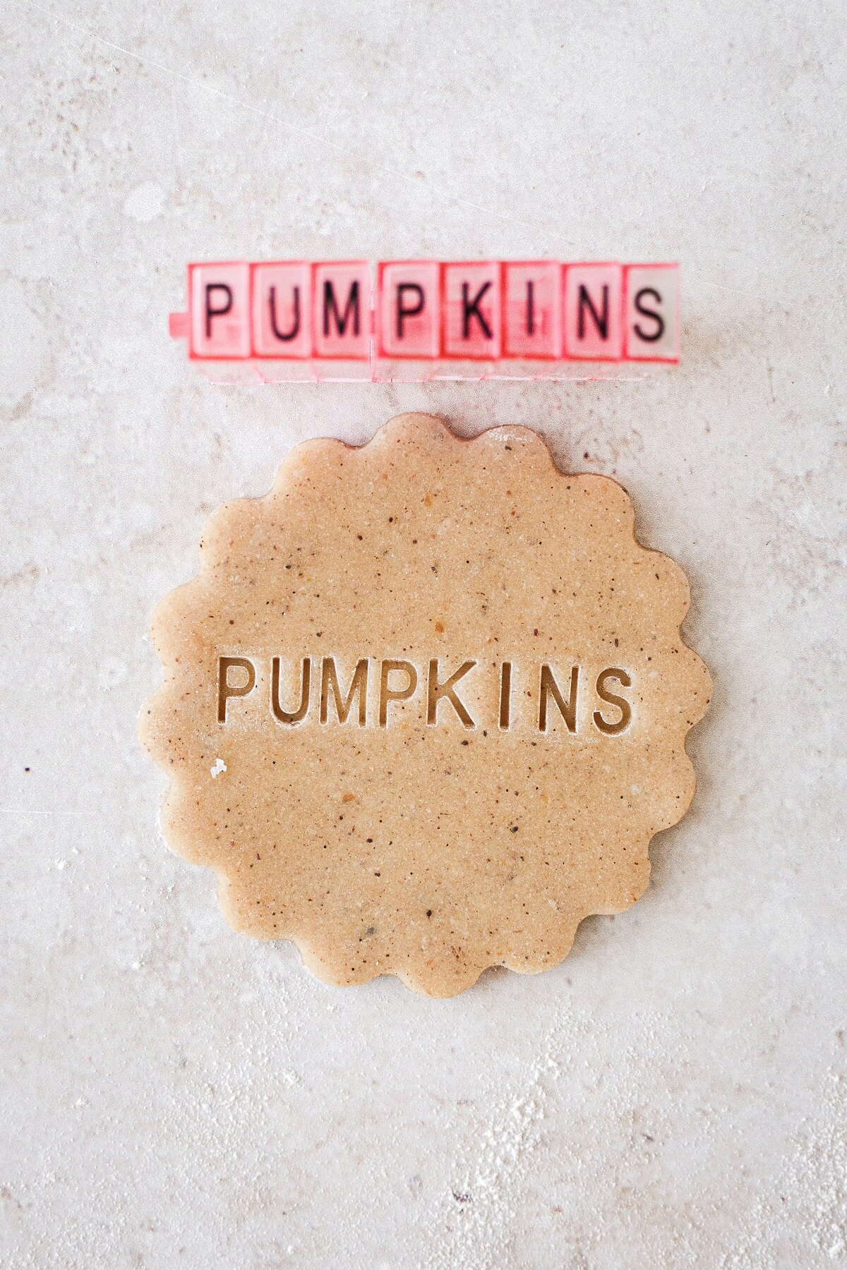 The word "pumpkins" stamped onto a cookie.