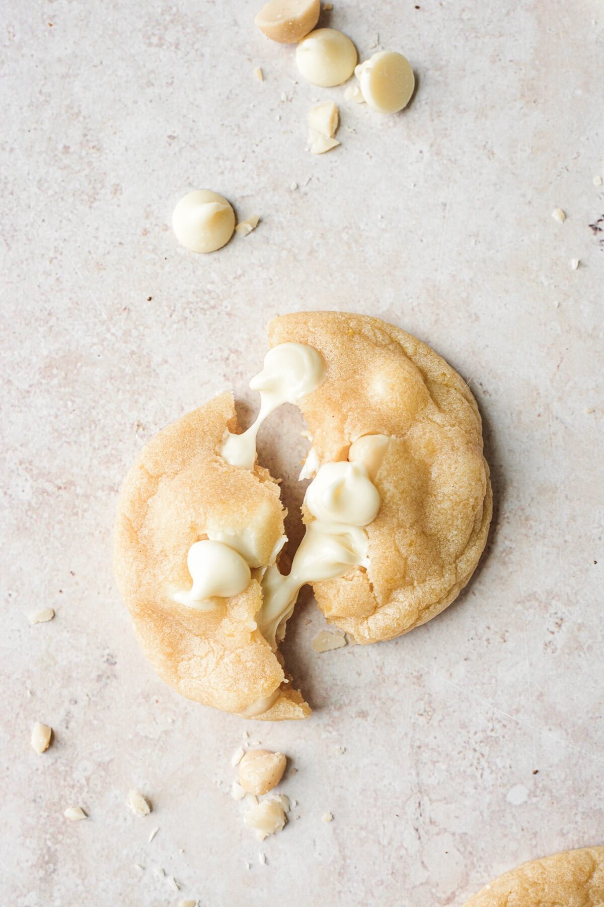 A soft lemon cookie with white chocolate chips broken in half.
