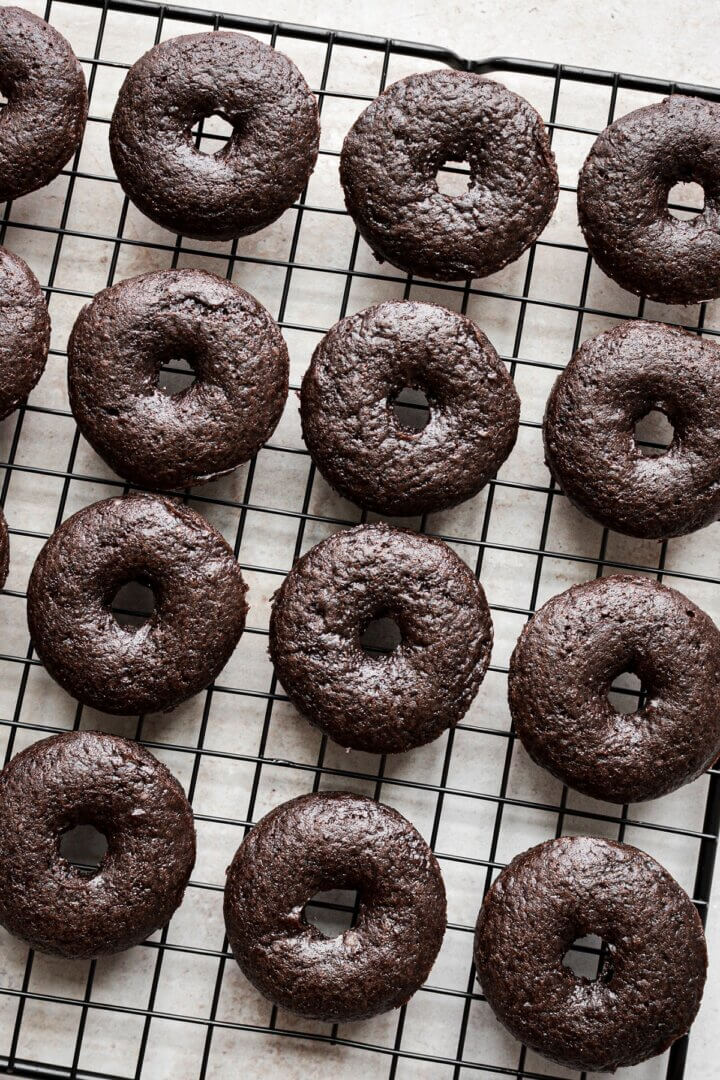 Mini baked chocolate cake doughnuts on a cooling rack.