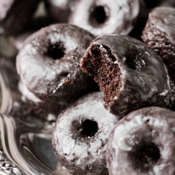 Mini baked chocolate cake doughnuts, one with a bite taken.