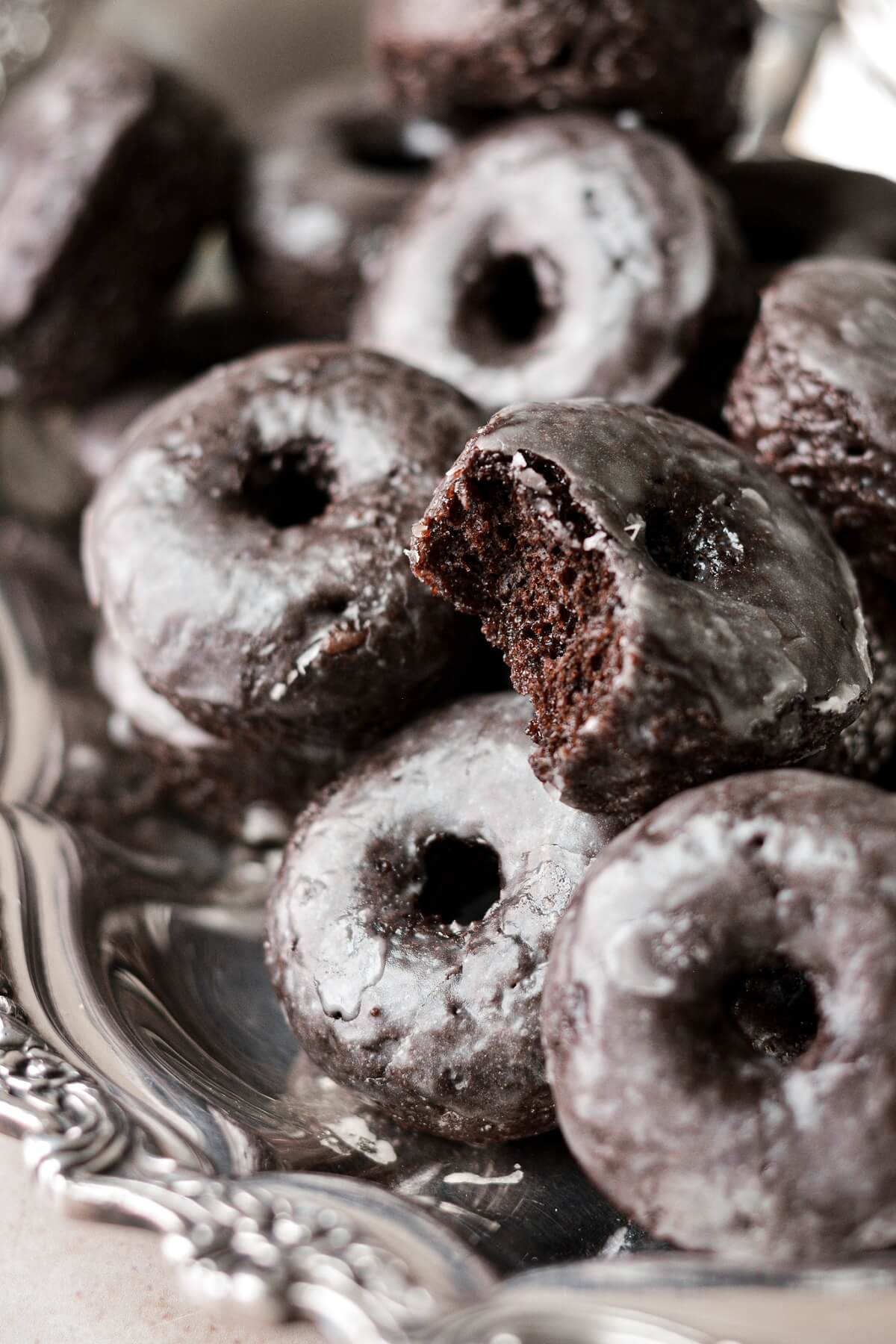 Mini baked chocolate cake doughnuts, one with a bite taken.
