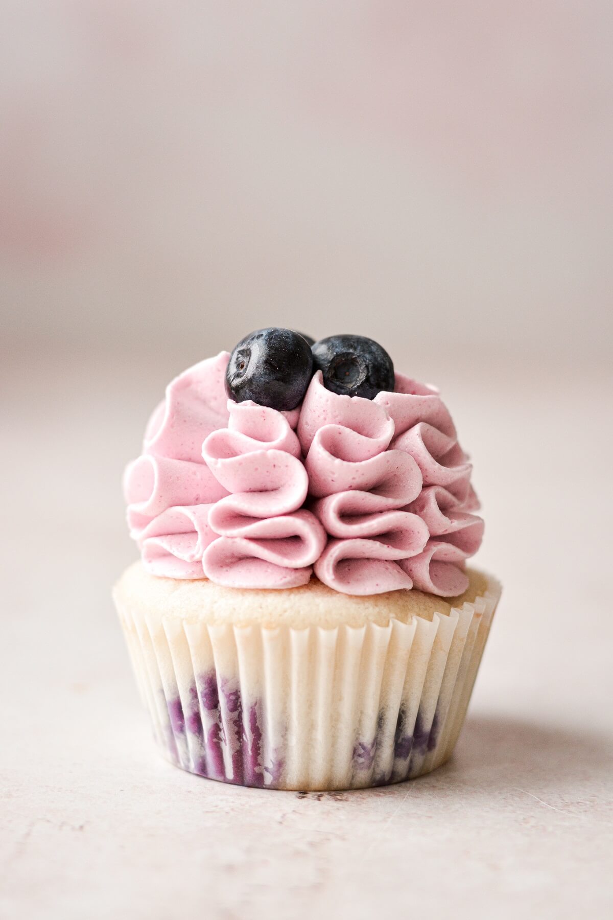 A blueberry cupcake with ruffled buttercream.
