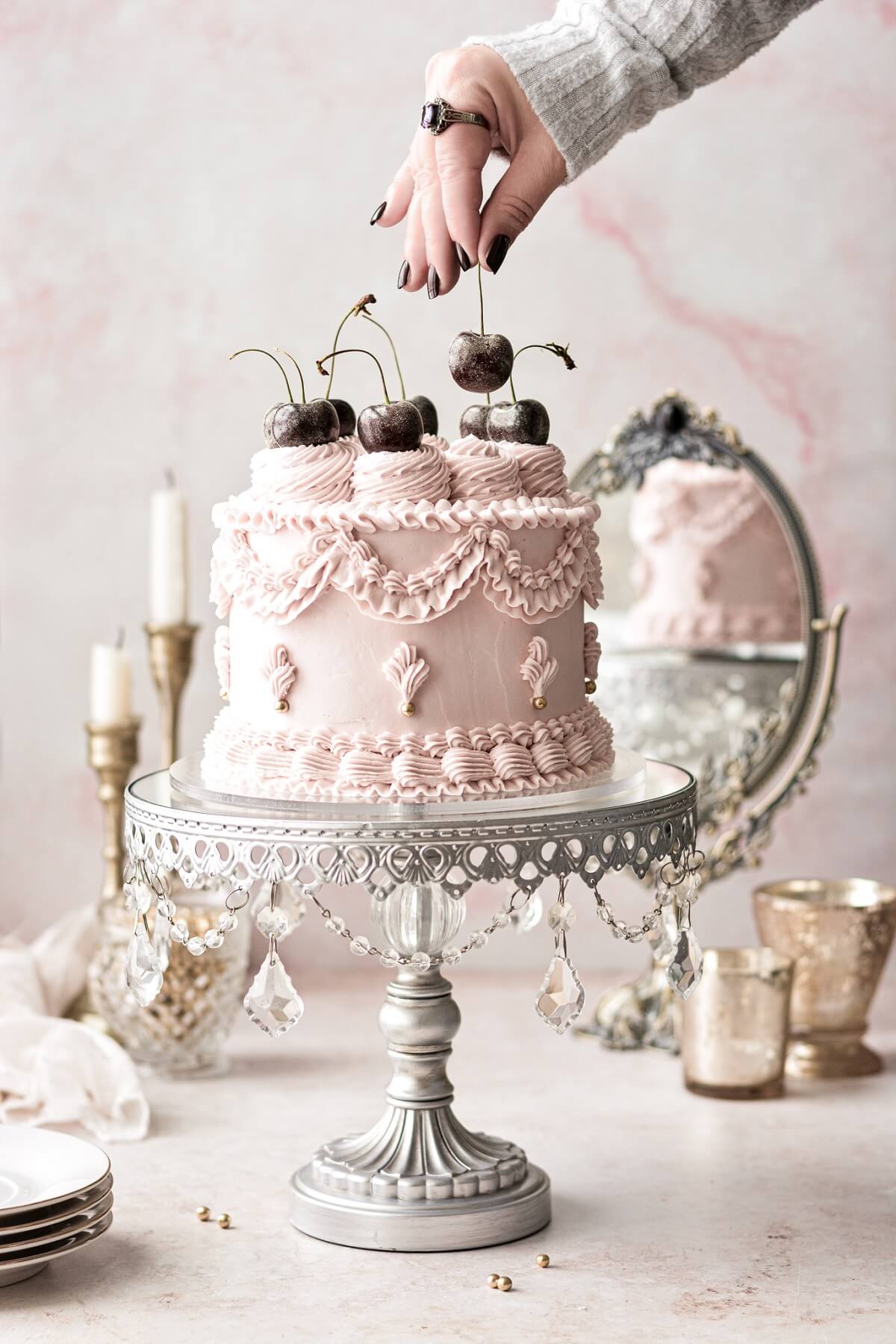 Cherries being placed on top of a pink lambeth cake.