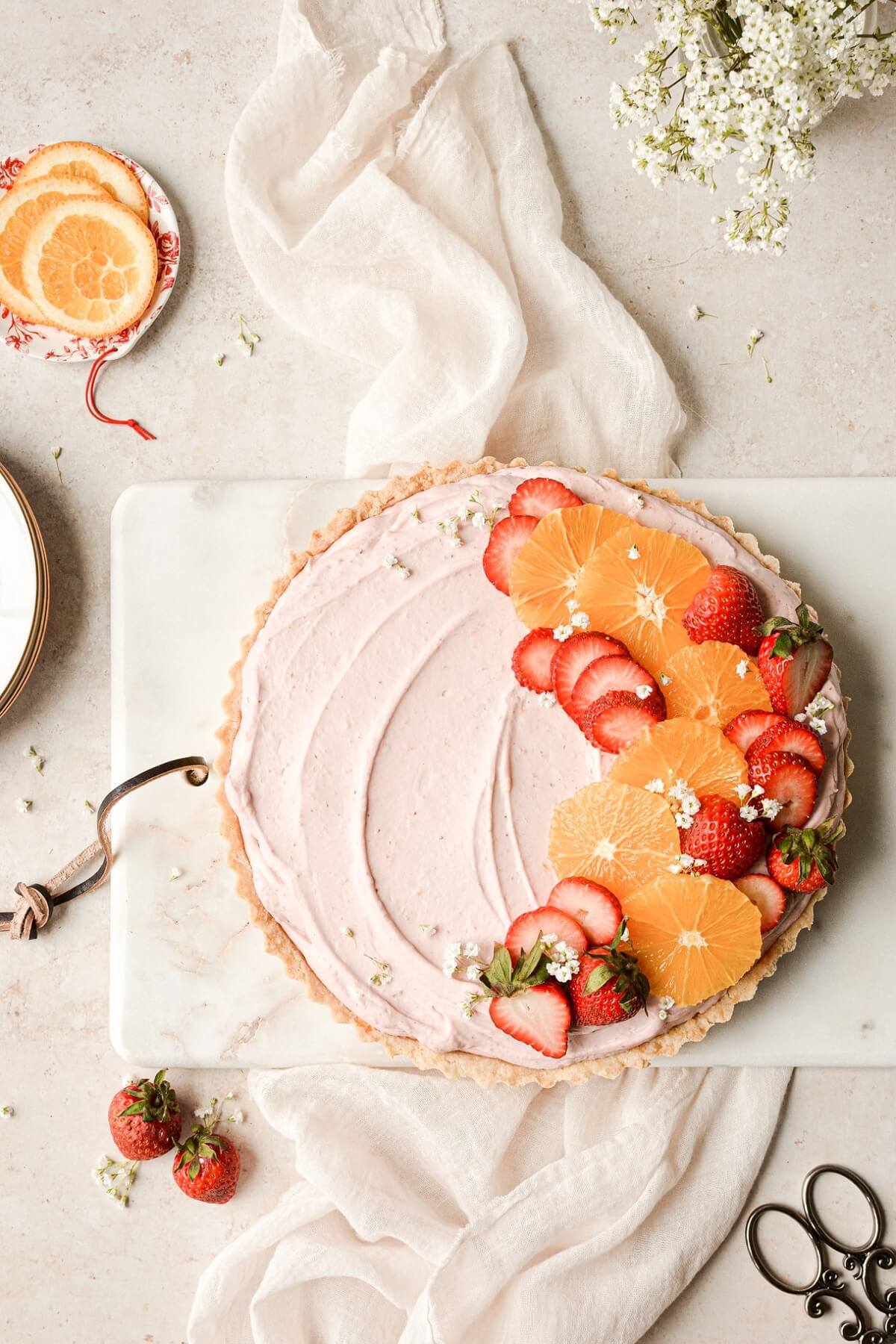 Strawberry orange cream pie decorated with sliced oranges and strawberries.