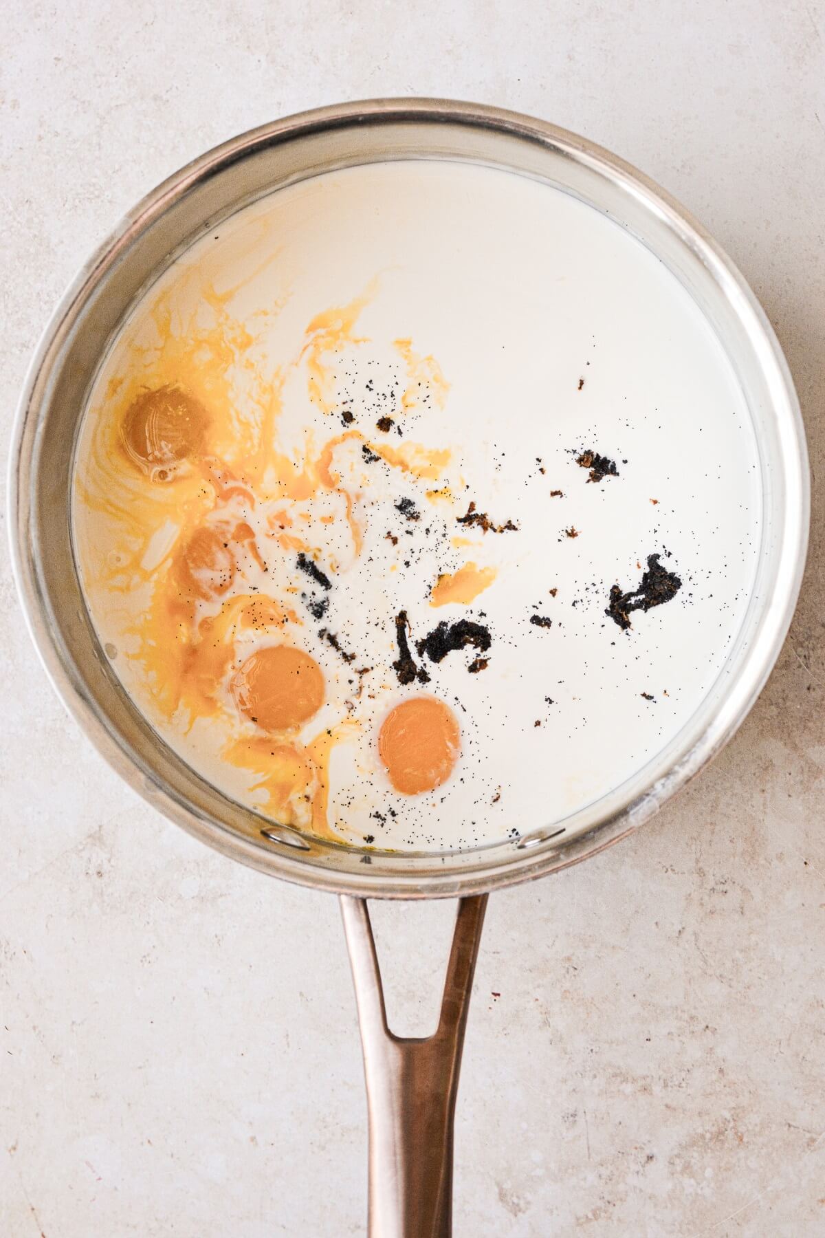 Egg yolks, cream and vanilla bean in a saucepan.