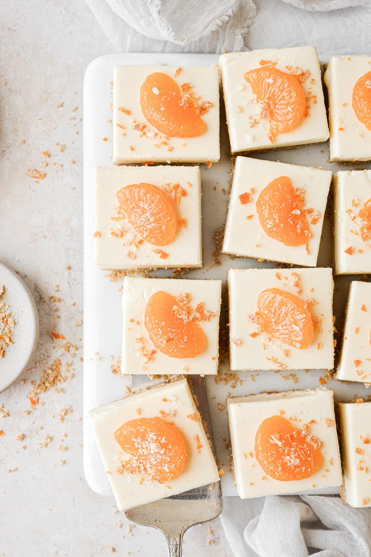 No bake orange creamsicle cheesecake bars cut into squares and topped with mandarin orange slices.