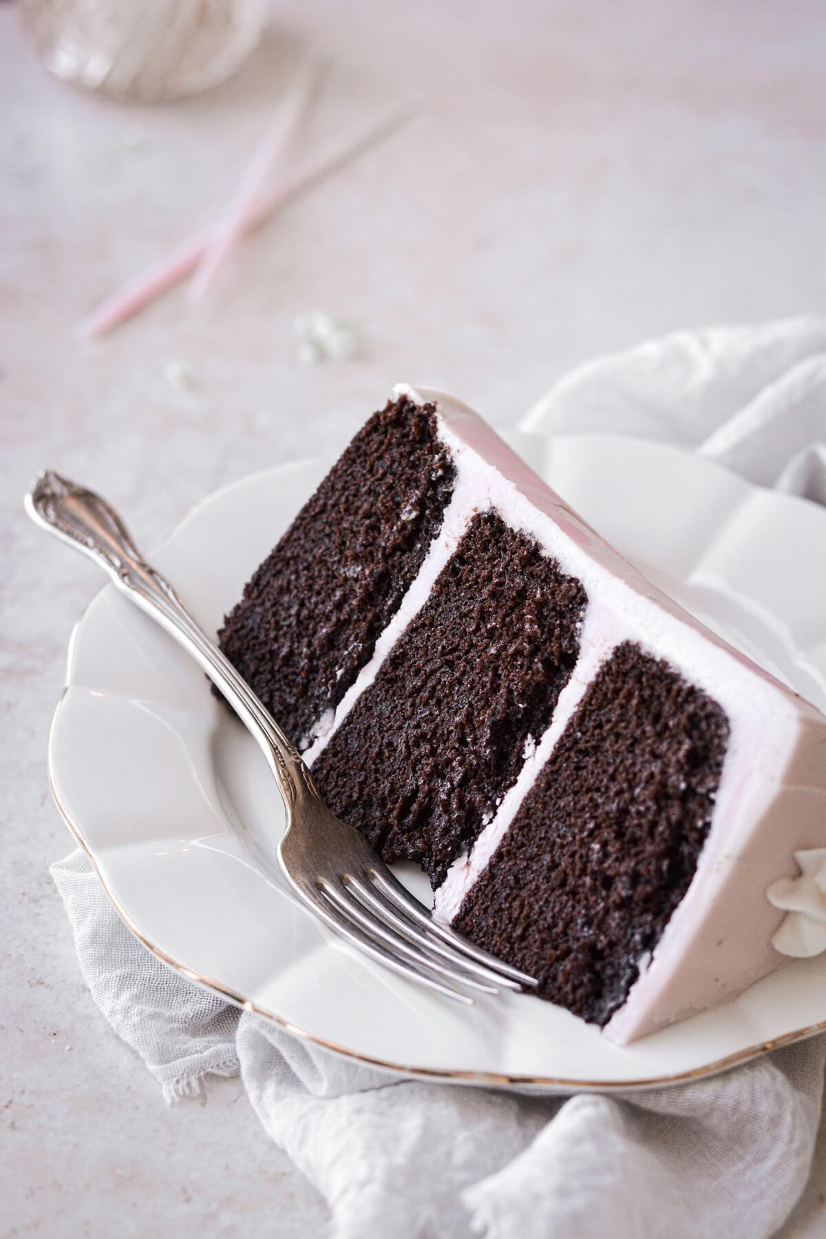 A slice of chocolate cake with pink buttercream.