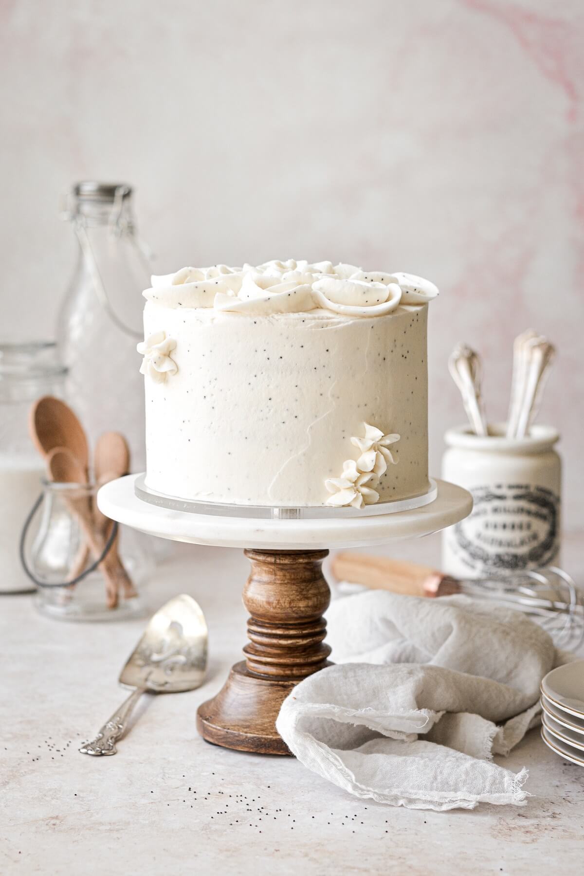 Almond poppy seed cake on a wood and marble cake stand.