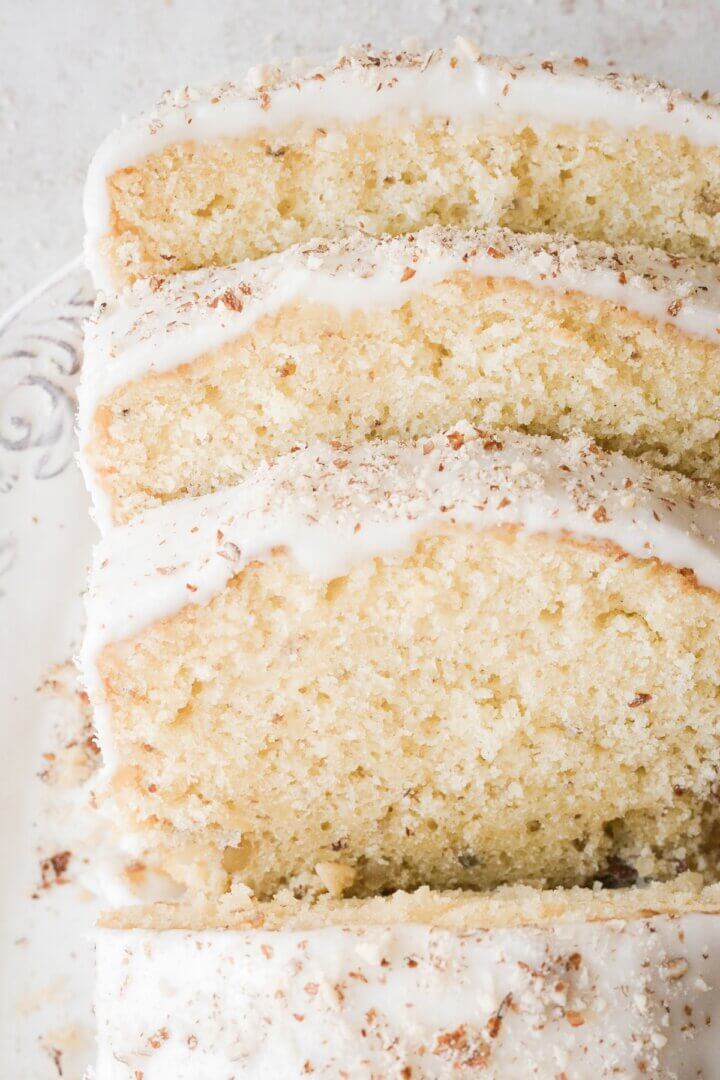 Slices of cardamom almond loaf cake with almond icing.
