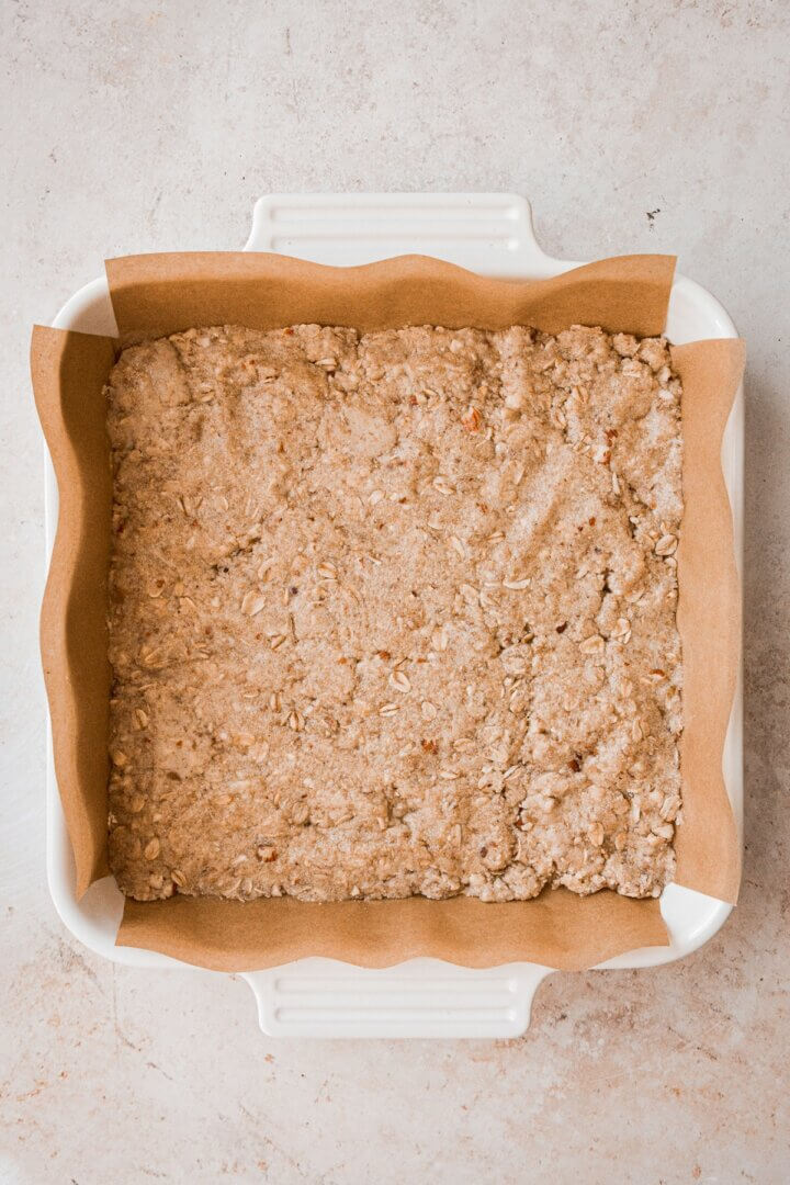 Almond oat crumb mixture pressed into a baking dish.