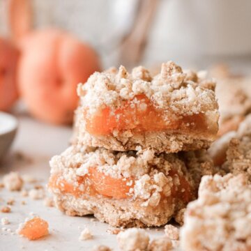 Apricot almond oat bars stacked next to fresh apricots.