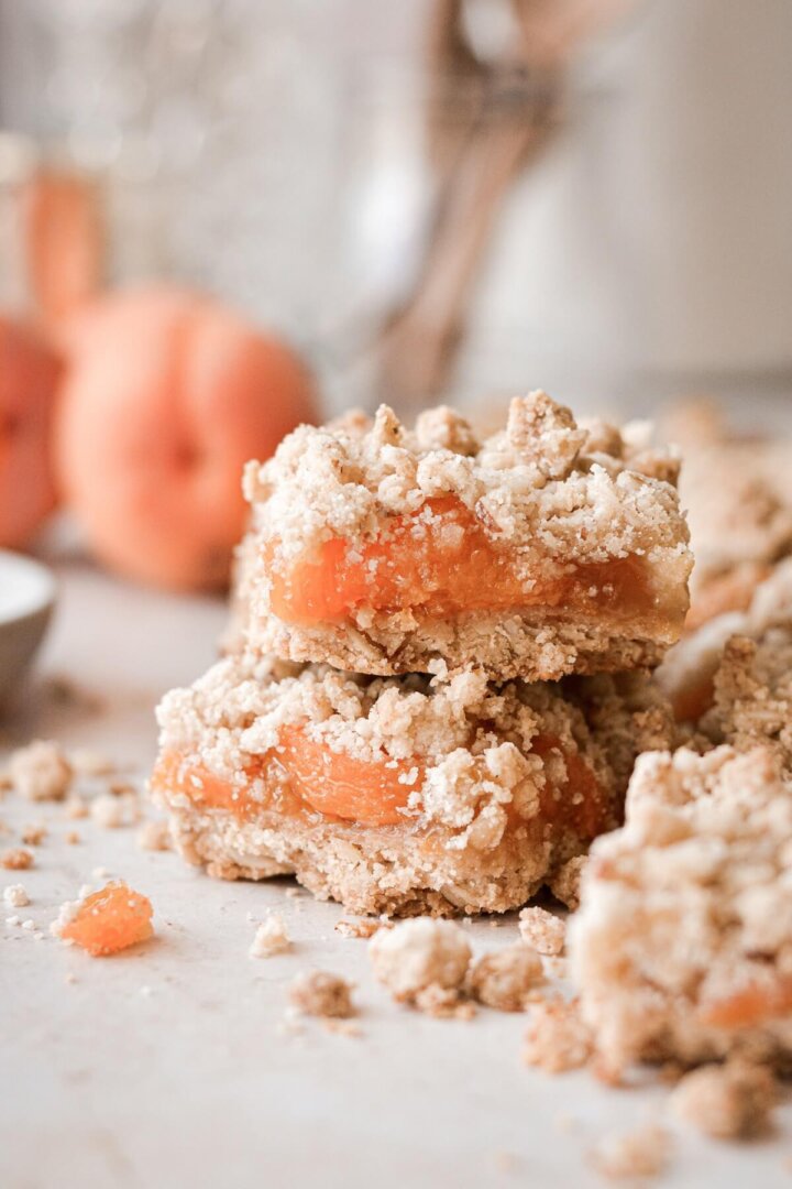 Apricot almond oat bars stacked next to fresh apricots.
