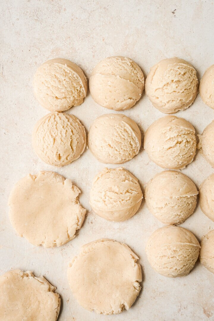Balls of sugar cookie dough pressed flat.