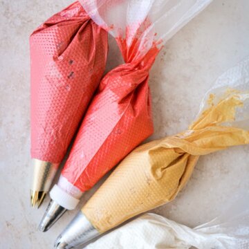 Piping bags filled with red, yellow and white buttercream.