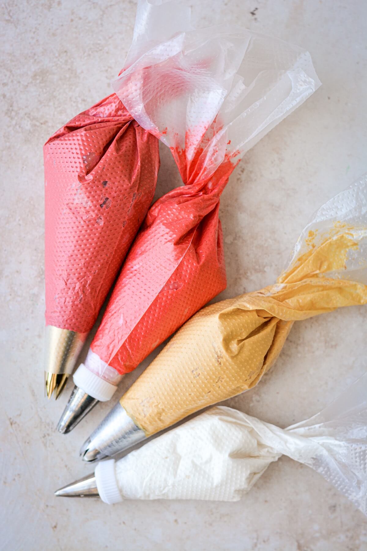 Piping bags filled with red, yellow and white buttercream.