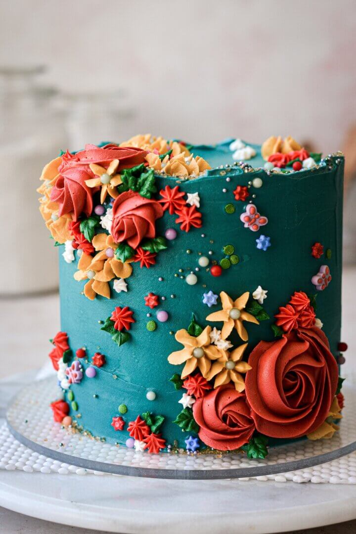 Turquoise floral cake with piped flowers and sprinkles.