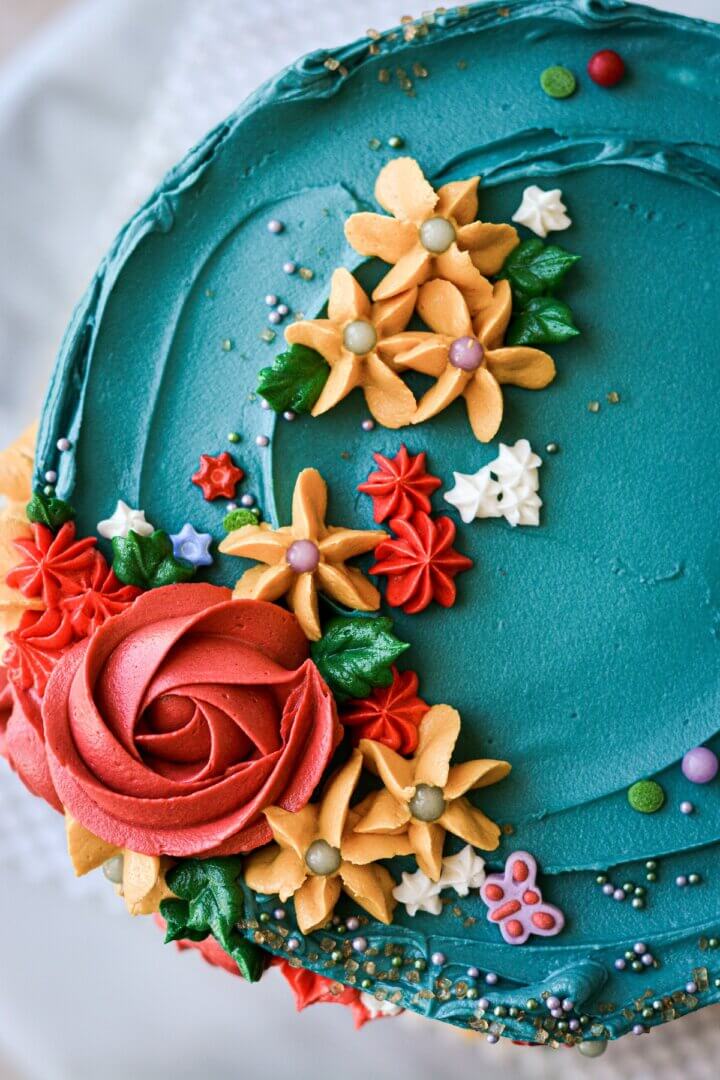 Buttercream flowers piped on top of a turquoise cake.