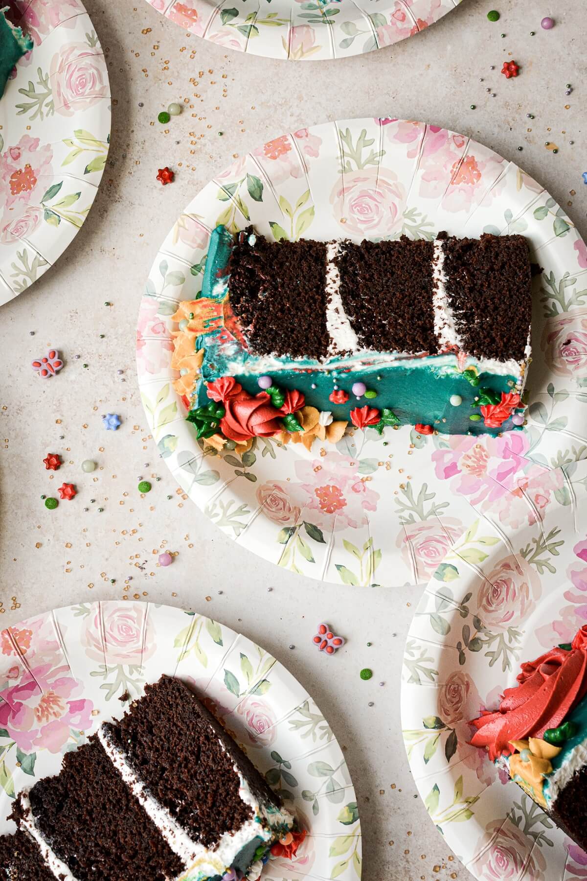 Slices of chocolate cake on floral paper plates.