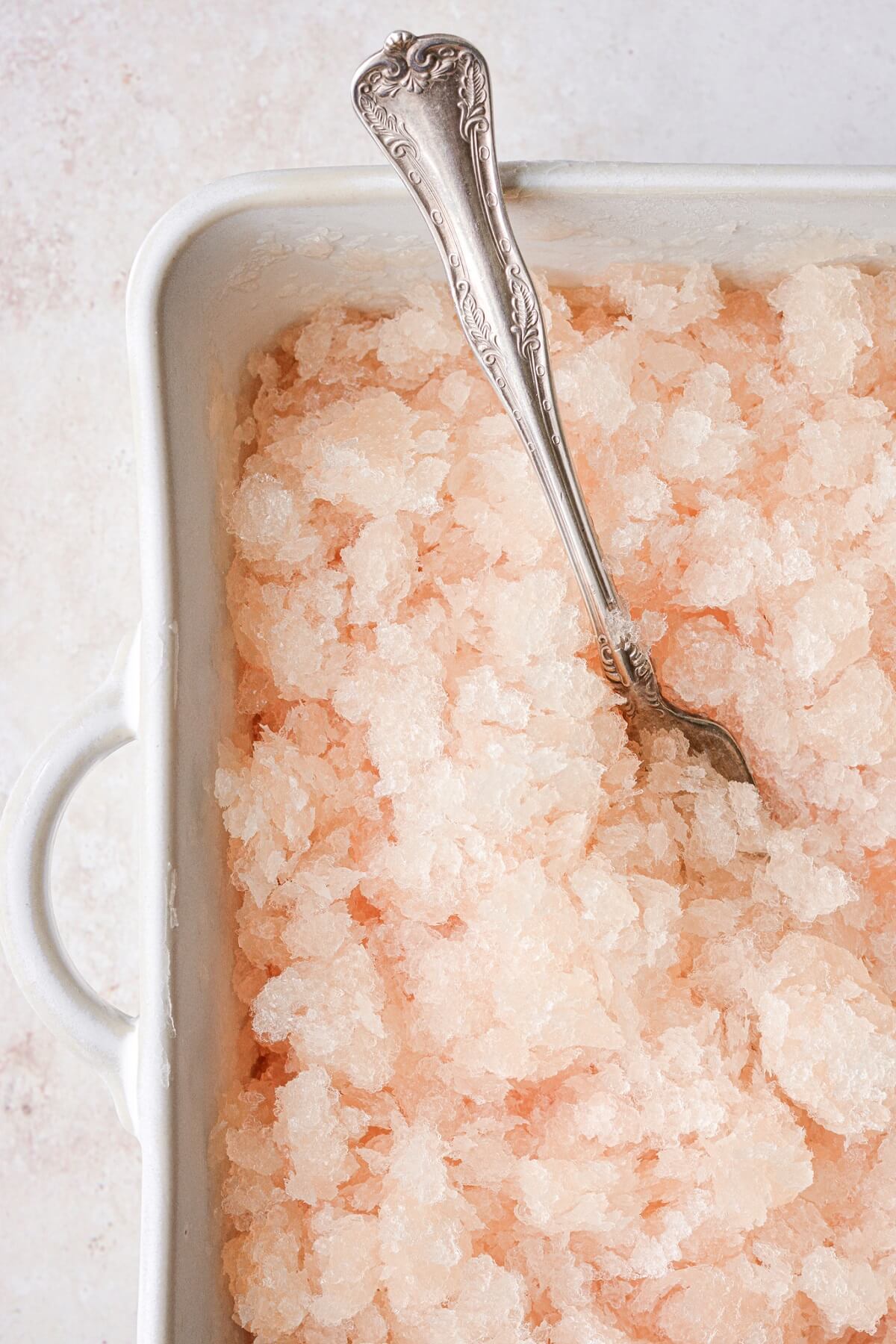 Grapefruit champage granita being stirred with a fork.