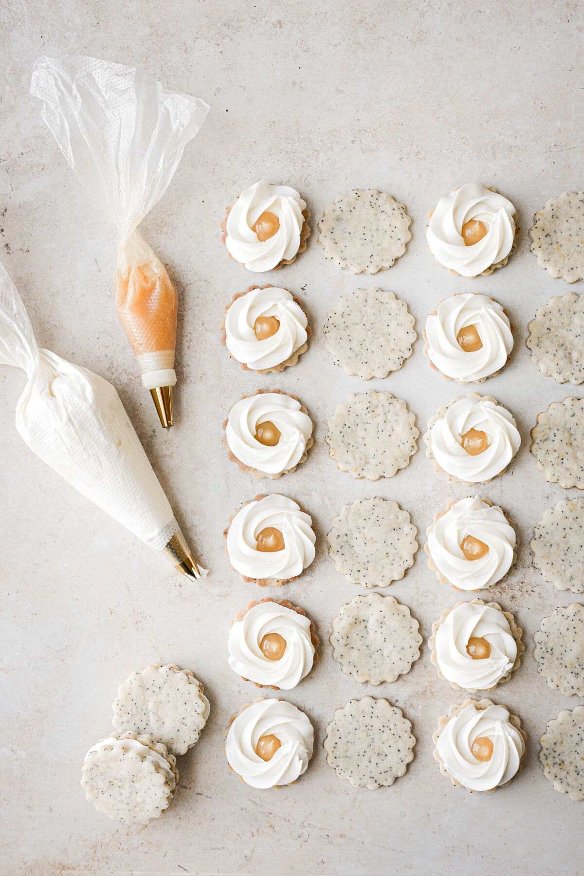 Lemon poppy seed shortbread cookies being filled with lemon buttercream and lemon curd.