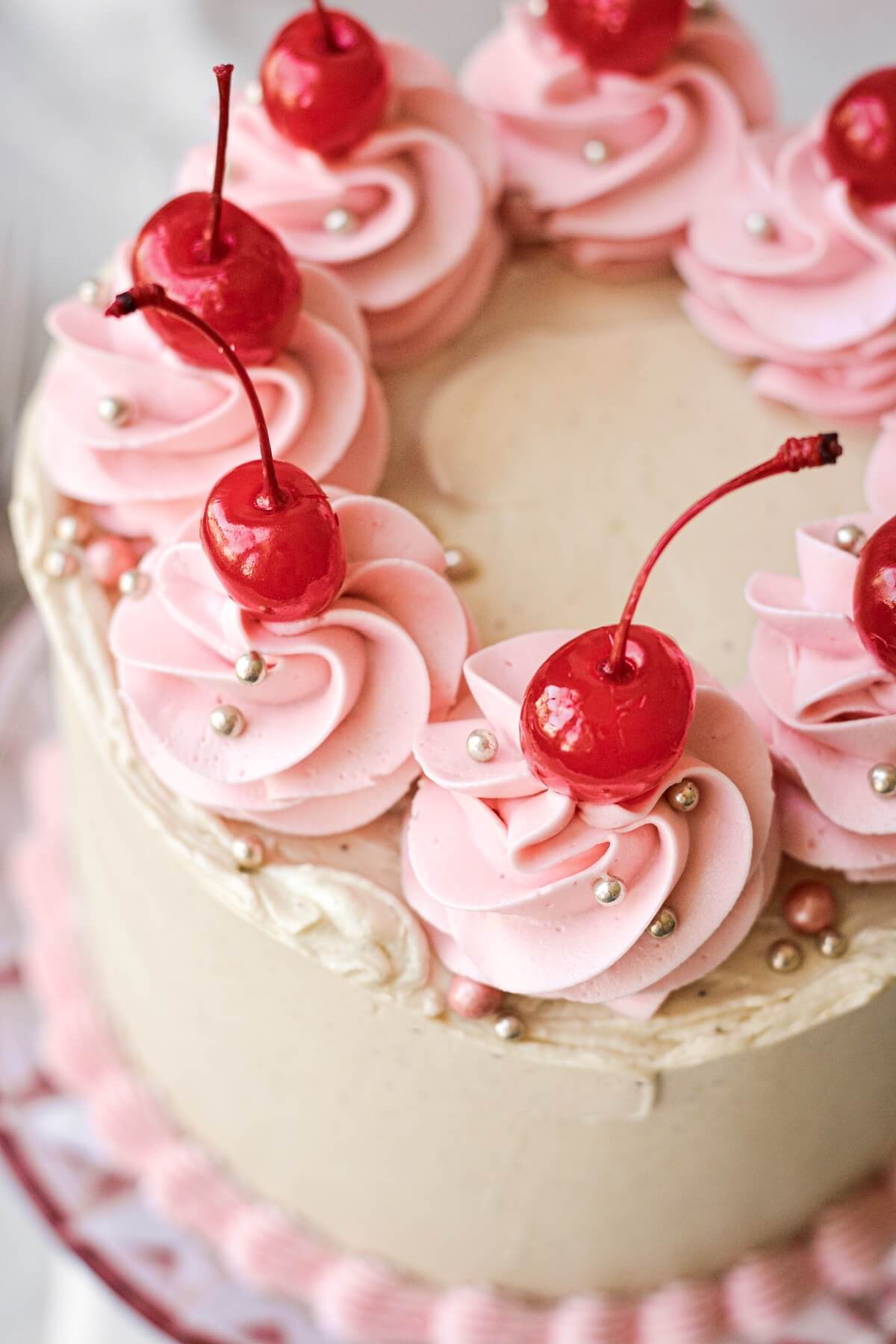 Maraschino cherries and gold sugar pearls on a cherry pistachio layer cake.