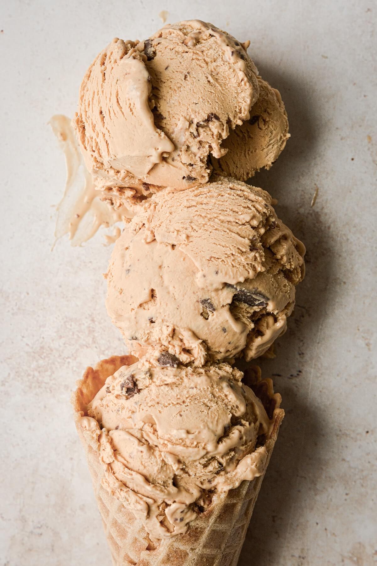 Scoops of no churn dulce de leche salted toffee ice cream in a waffle cone.