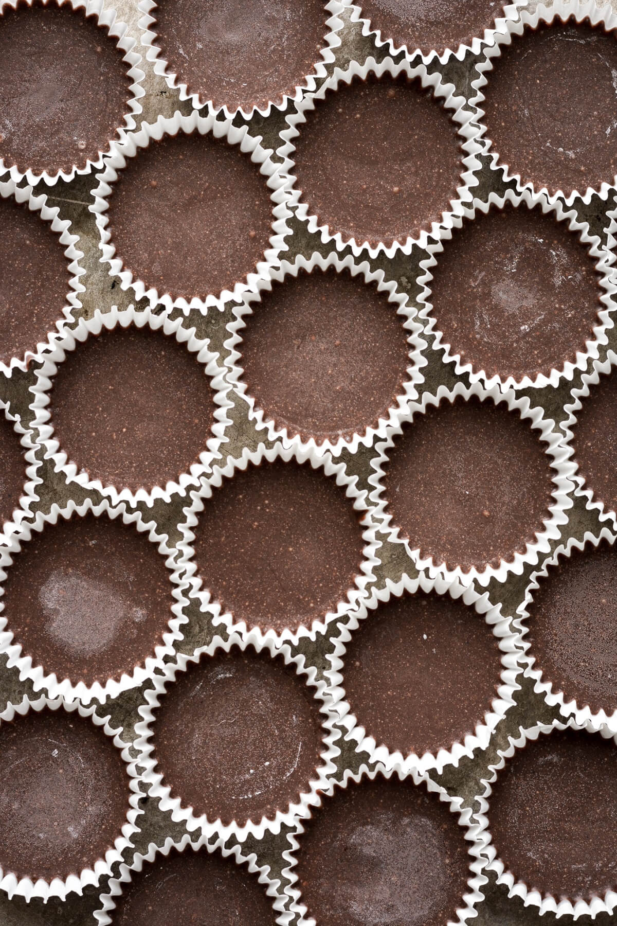 Frozen chocolate almond butter bites in white paper wrappers.