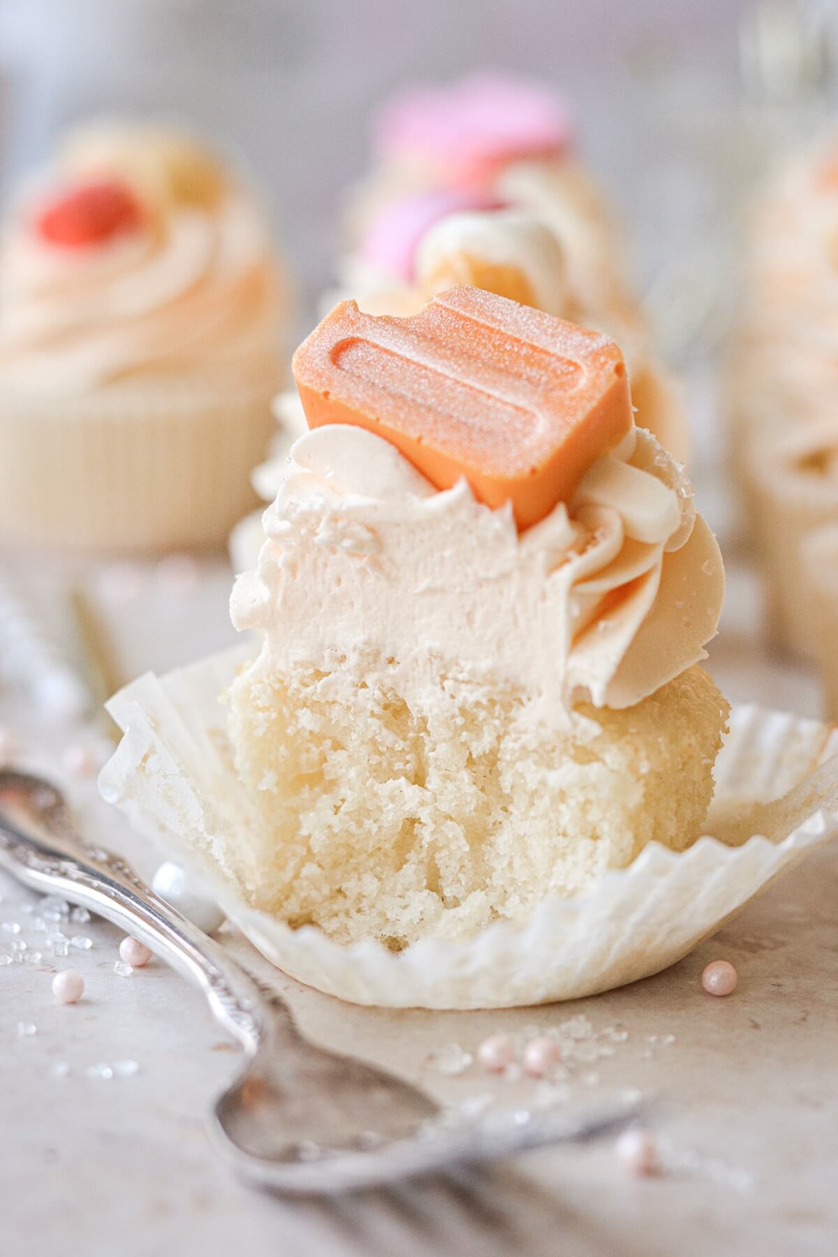 An orange creamsicle cupcake with a bite taken.