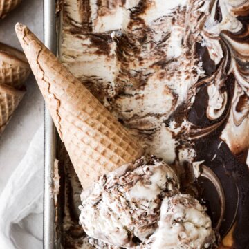 An ice cream cone with scoops of no churn peanut butter vanilla fudge ripple ice cream.