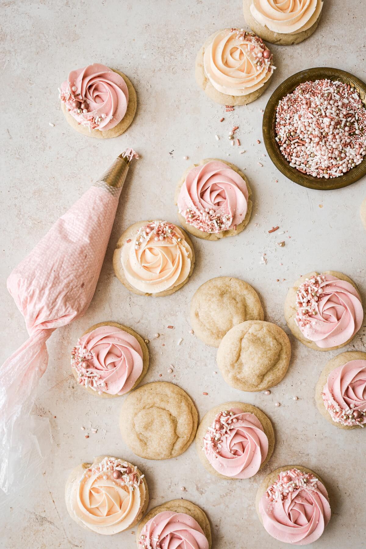 Soft sugar cookies with swirls of pink and orange buttercream and sprinkles.