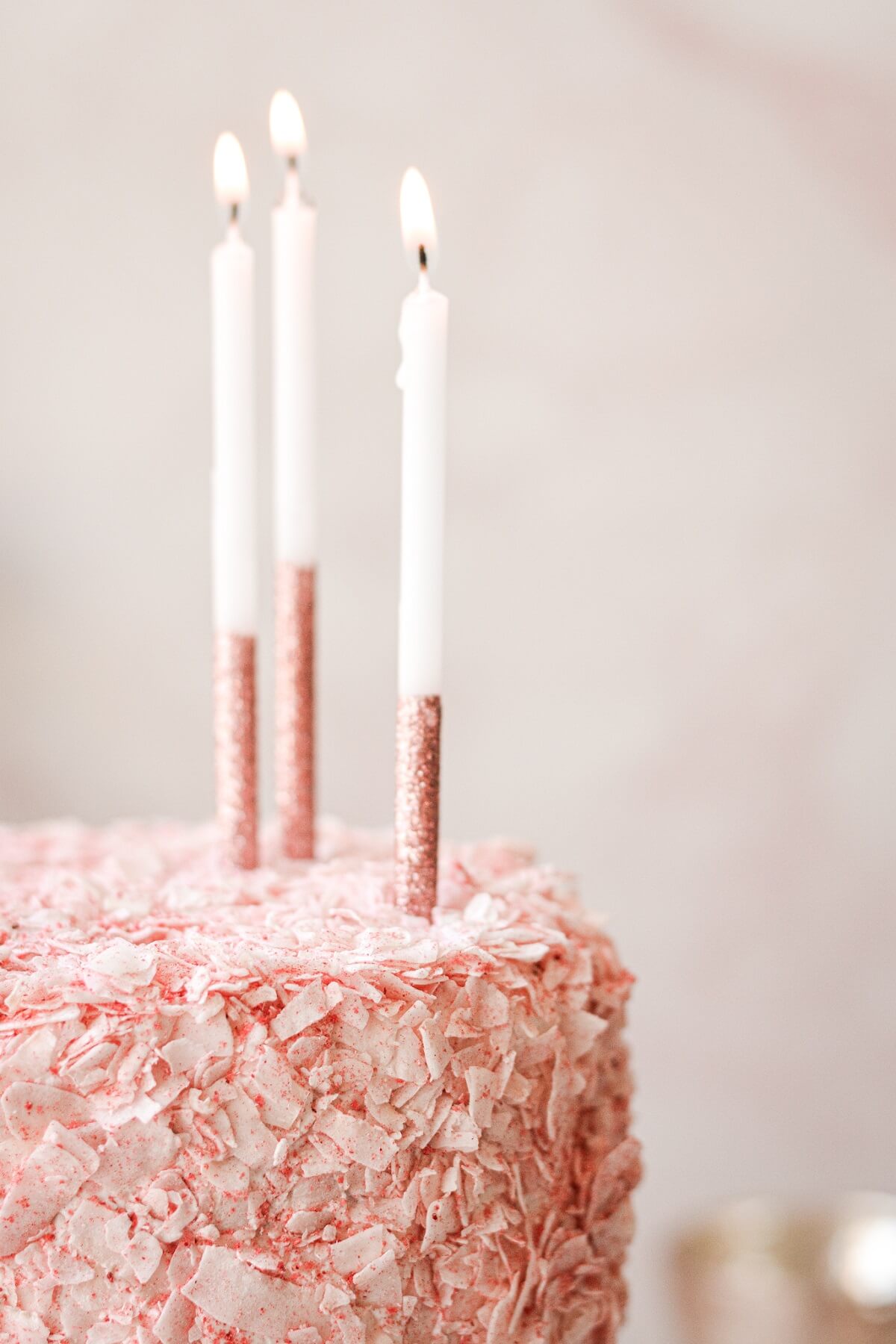 Pink and white candles on a strawberry coconut cake.