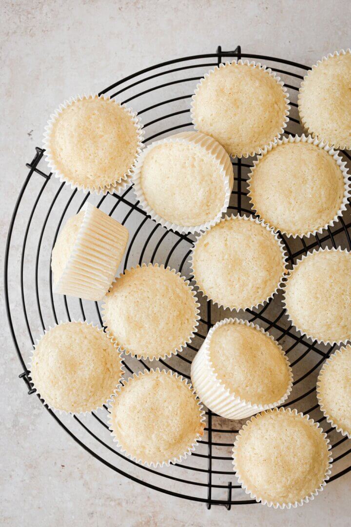 Almond cupcakes on a black cooling rack.