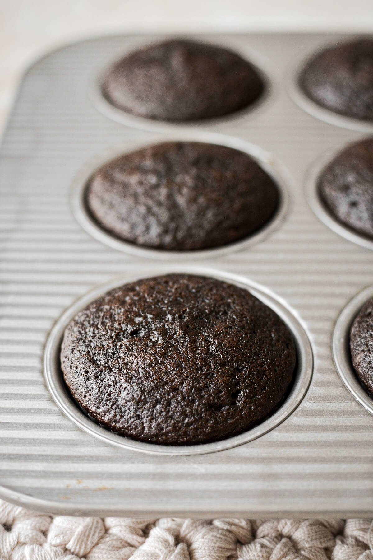 Chocolate cupcakes cooling in a muffin pan.