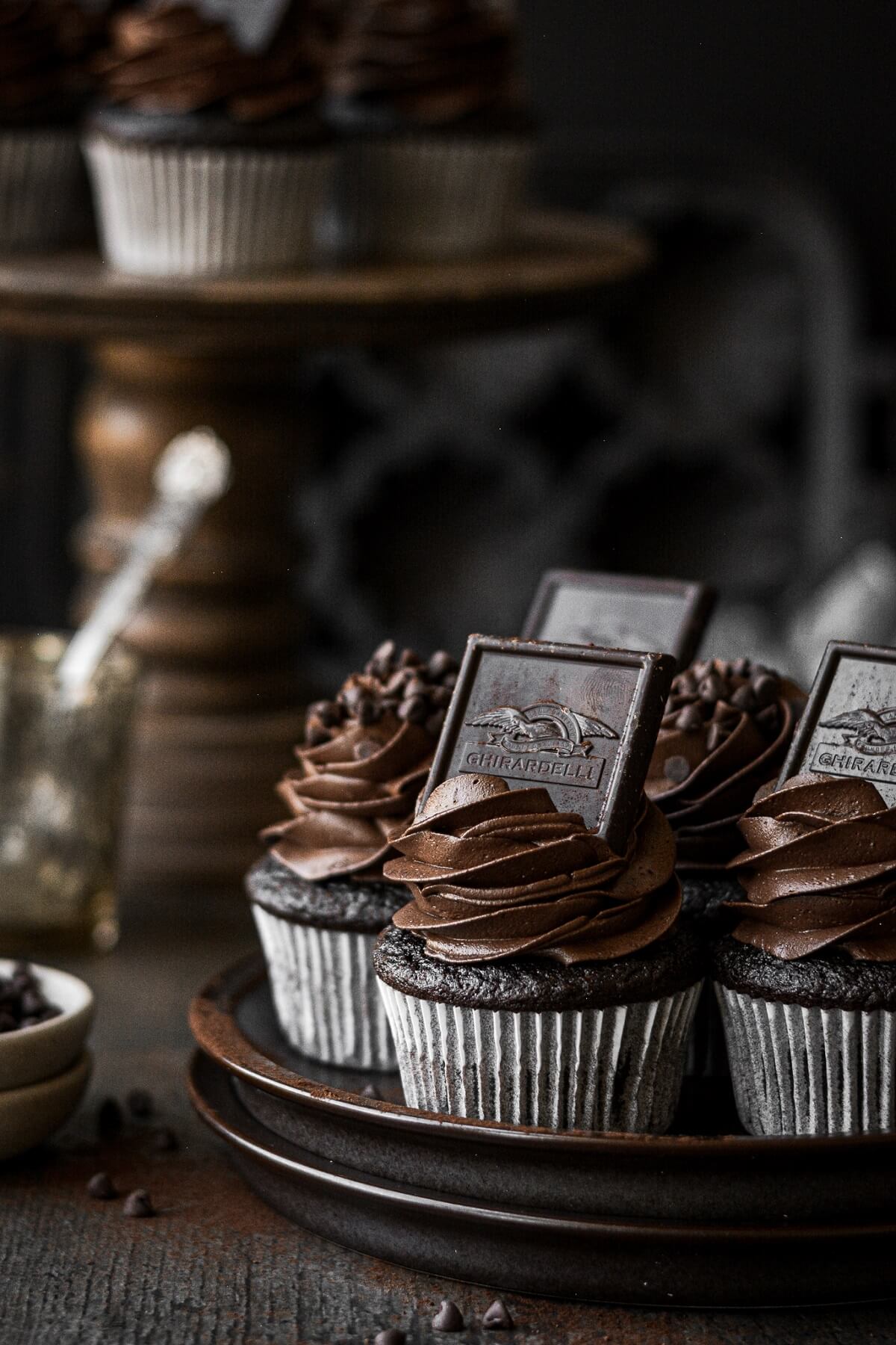 Chocolate cupcakes on a stack of plates.