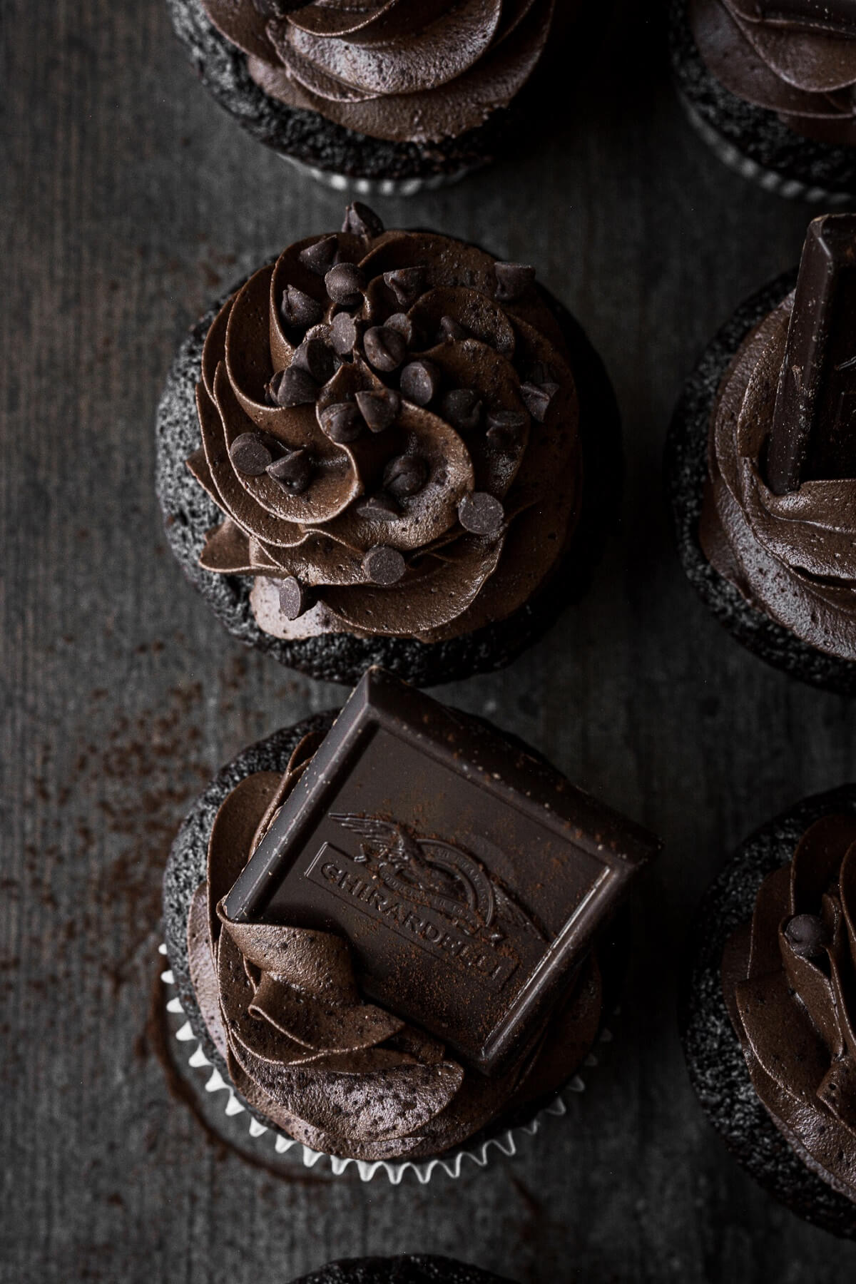 Chocolate cupcakes with chocolate frosting, squares of dark chocolate and chocolate chips.