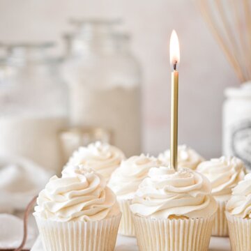 Vanilla cupcakes with a gold birthday candle.