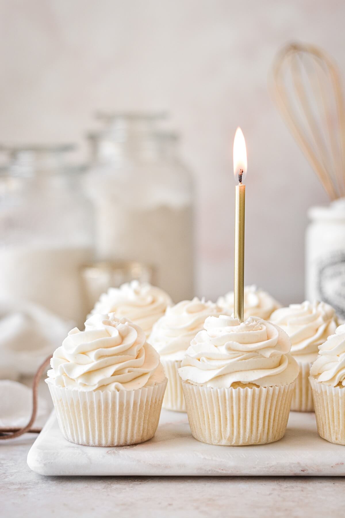 Vanilla cupcakes with a gold birthday candle.