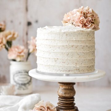 Hummingbird cake with pink carnations on a cake stand.