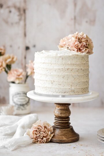 Hummingbird cake with pink carnations on a cake stand.
