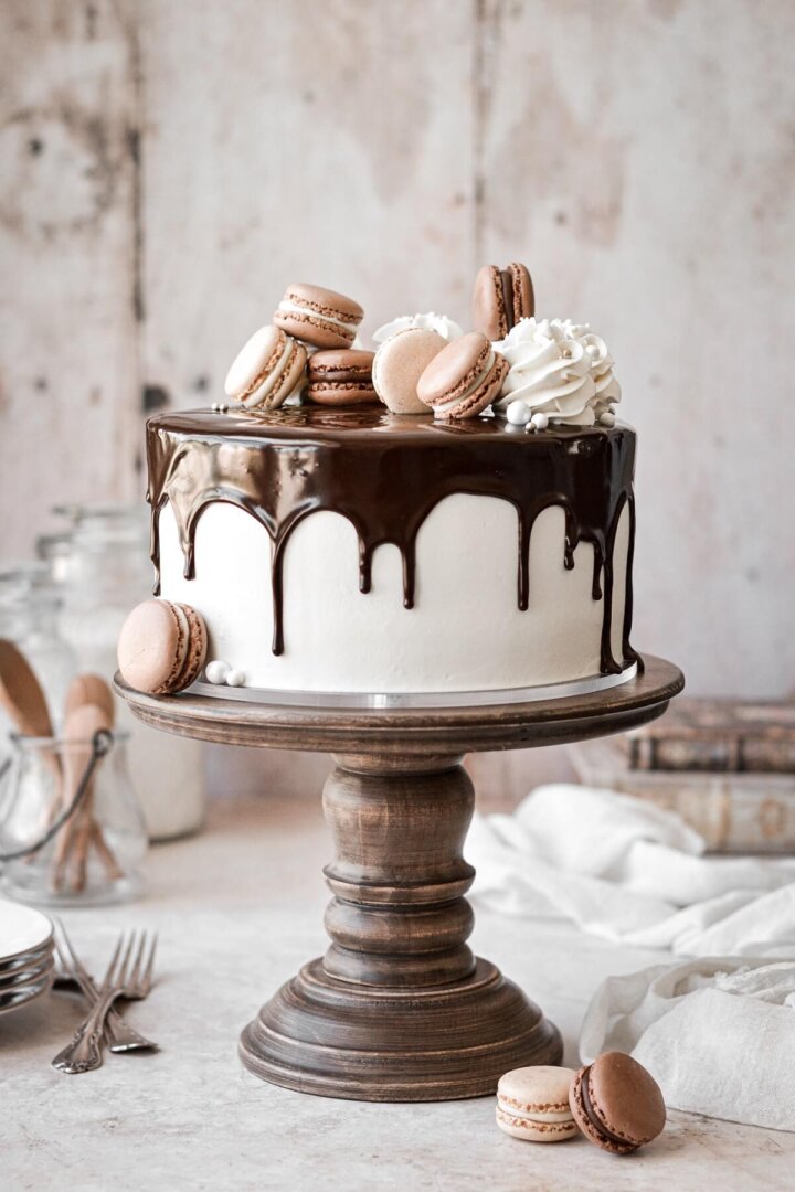 Marble cake with vanilla buttercream, chocolate ganache drip and macarons.