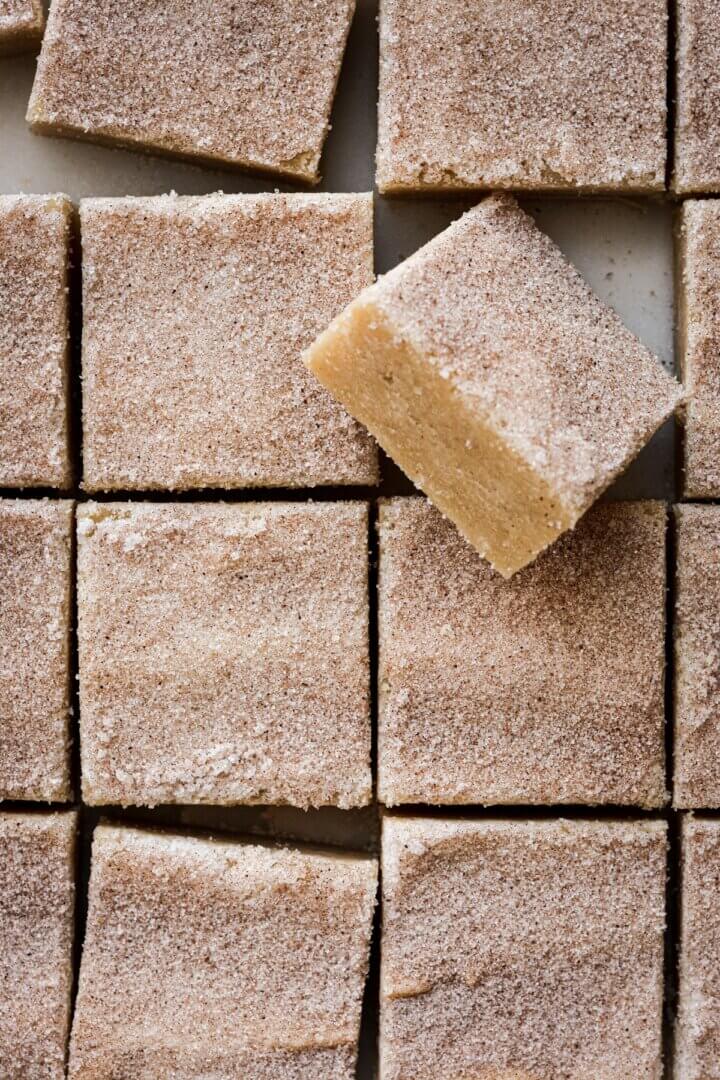 Snickerdoodle blondies cut into squares and sprinkled with cinnamon sugar.