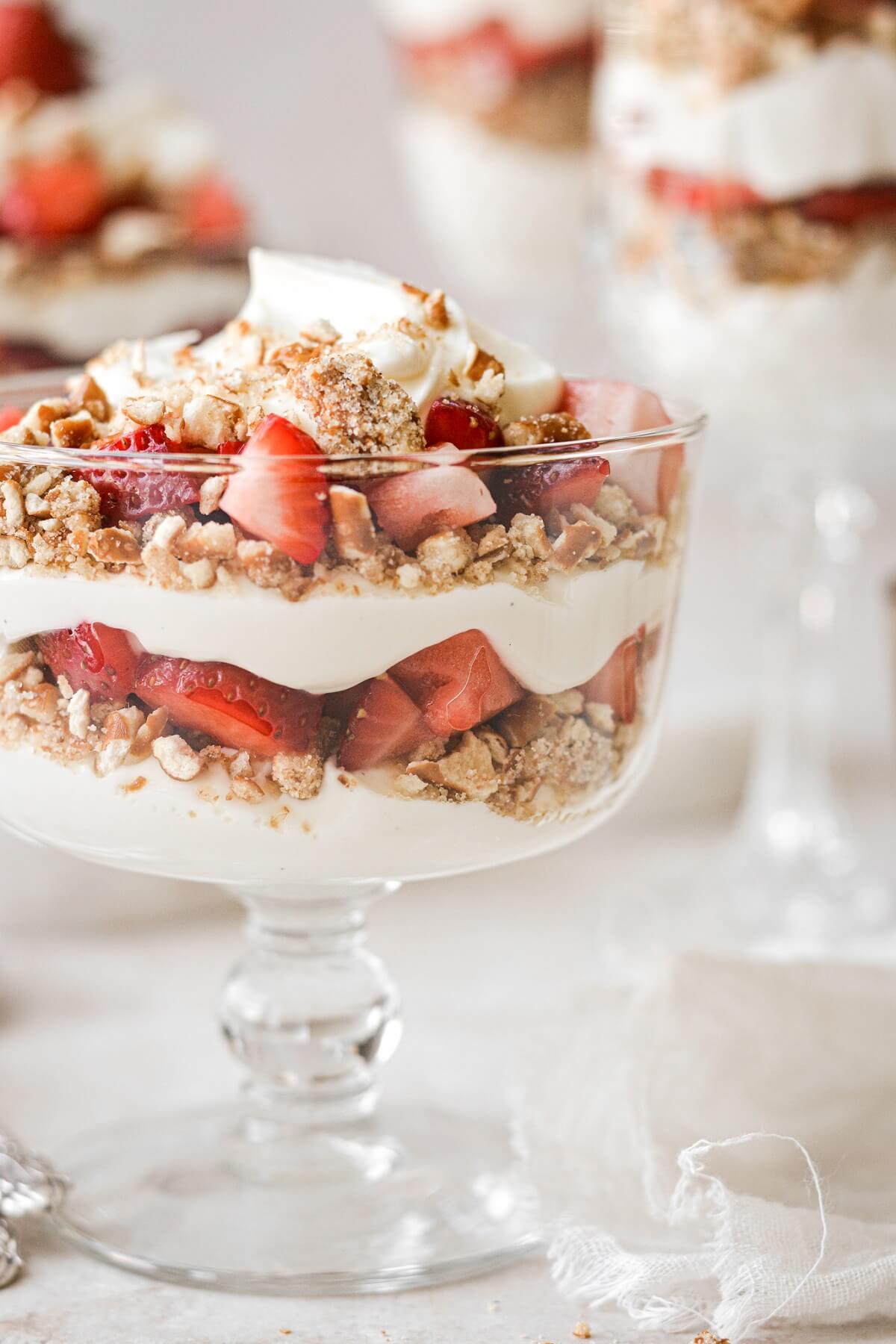 Layers of strawberries, whipped cream cheese and pretzels in a mini trifle dish.