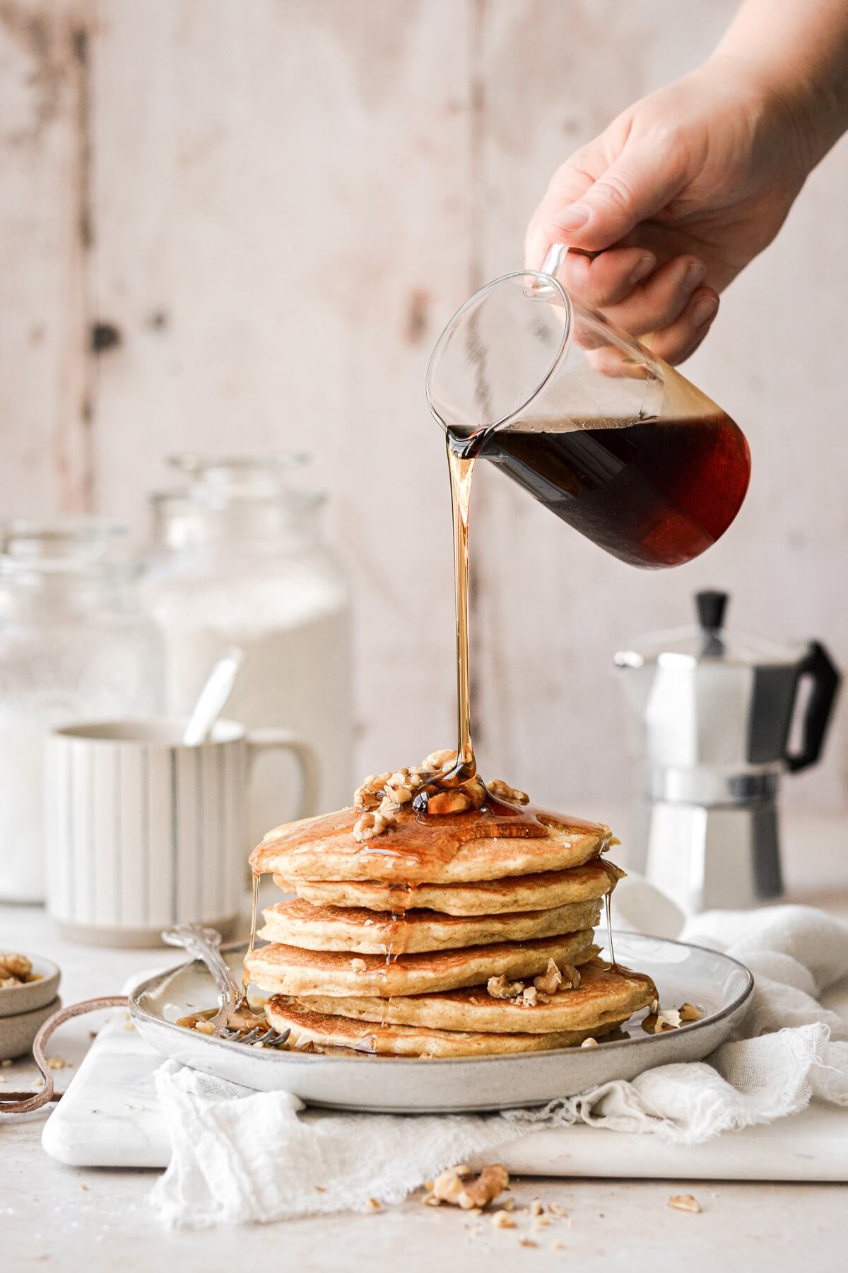Stack of whole wheat cornmeal pancakes with syrup being poured on top.